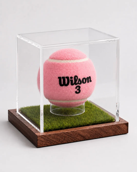 Angled view of a tennis ball display case with artificial grass and wooden base